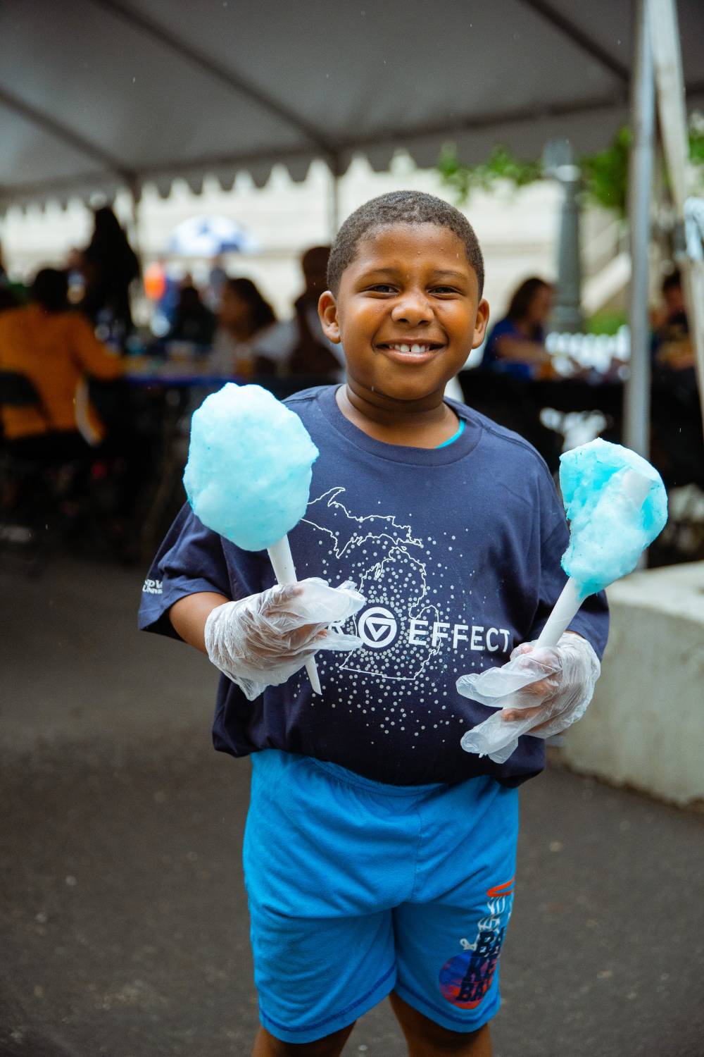 A cute kid in a gvsu laker effect T-shirt is helping serve cotton candy to the people at the party